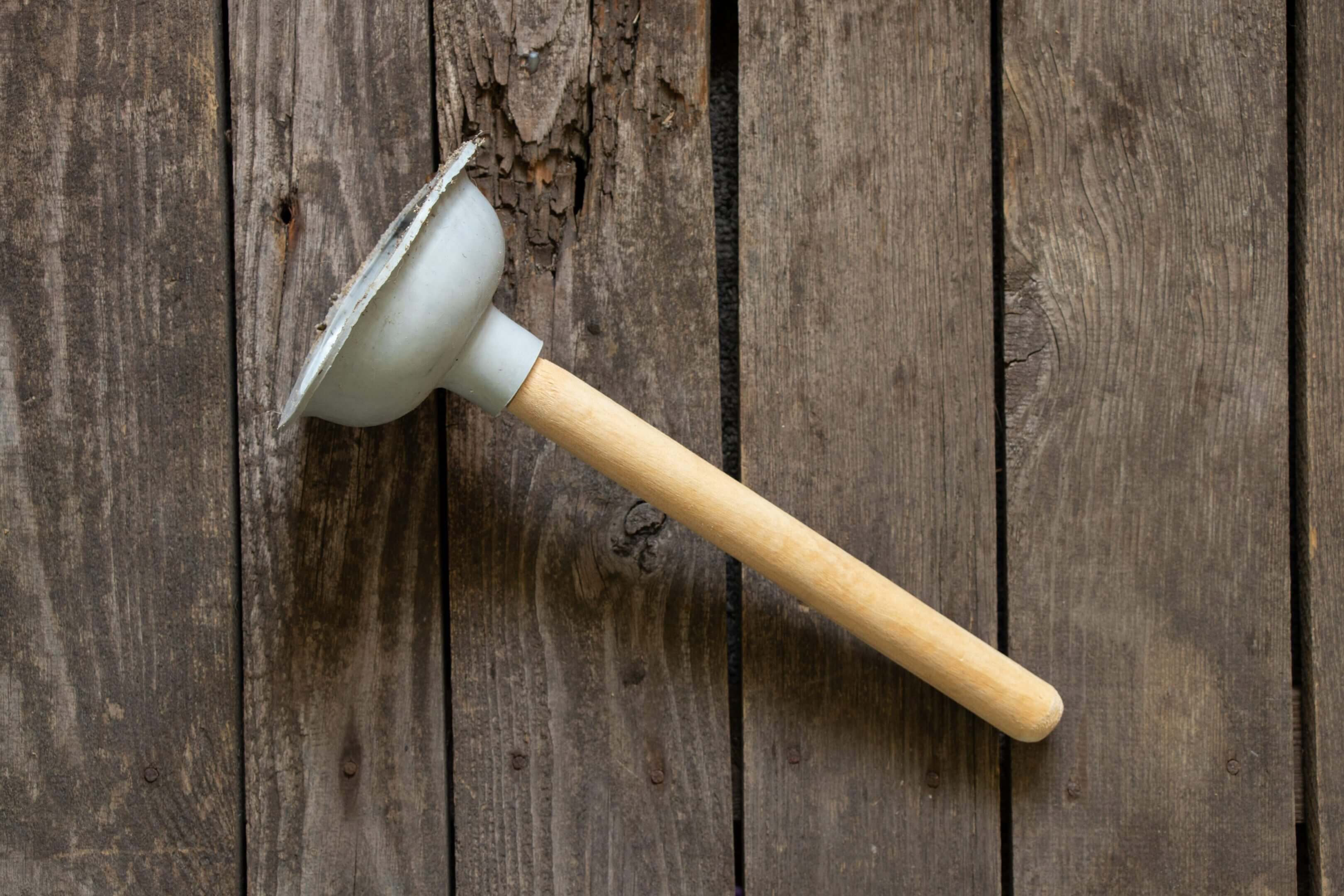 Old metal ladle on wooden background.