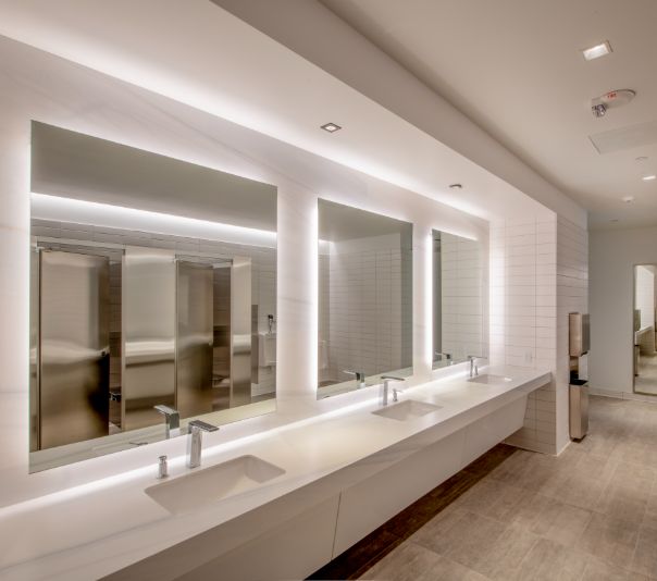 Modern public restroom with illuminated mirrors and clean design.