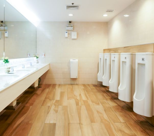 A clean, modern men's restroom with wooden floors and urinals.