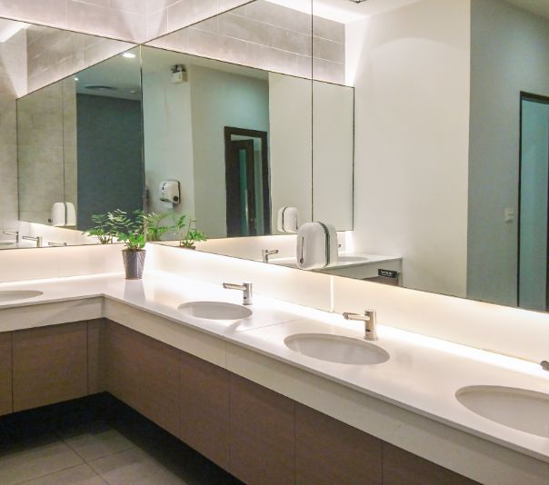 Modern public restroom with clean white sinks and large mirrors.