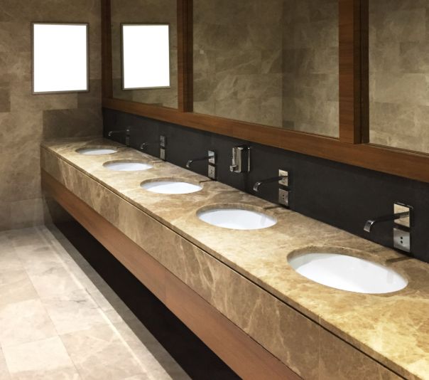 Modern public restroom with five sinks and large mirrors.