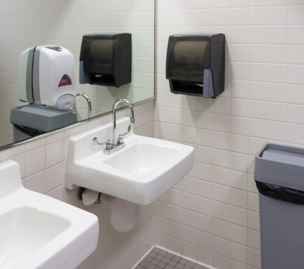 Clean, modern public restroom with white sinks and wall-mounted dispensers.