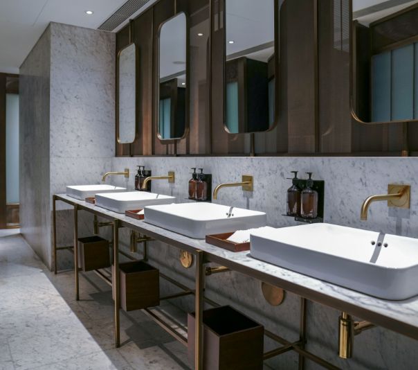 Modern bathroom with double sinks and wooden stools.