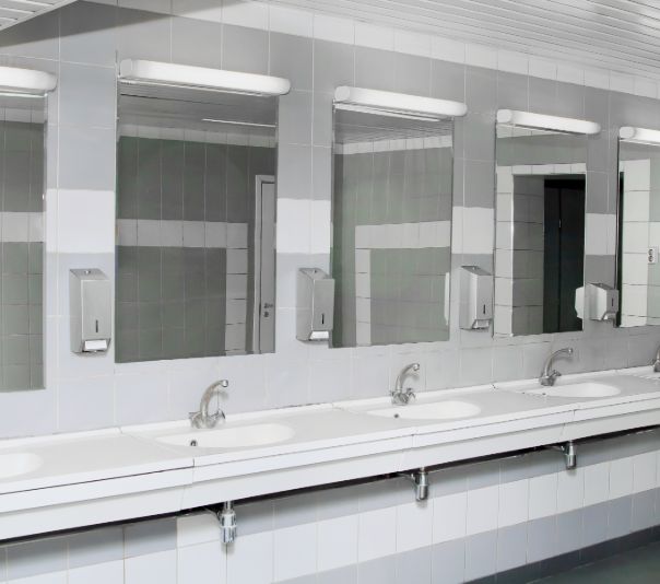 Modern public restroom sinks with large mirrors and soap dispensers.