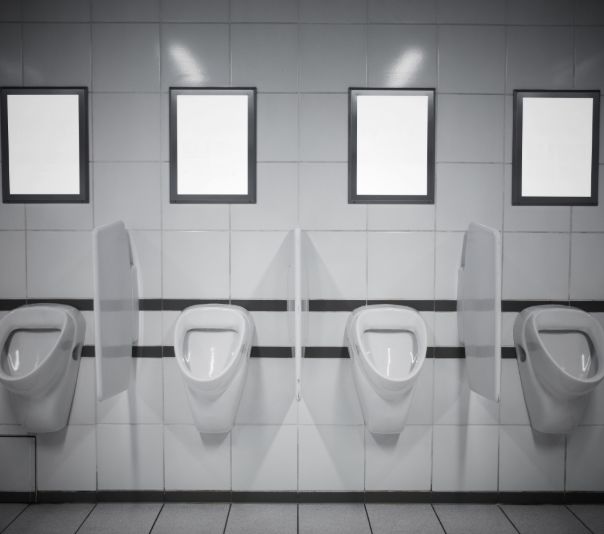 A row of white urinals in a public restroom with black and white tiles.