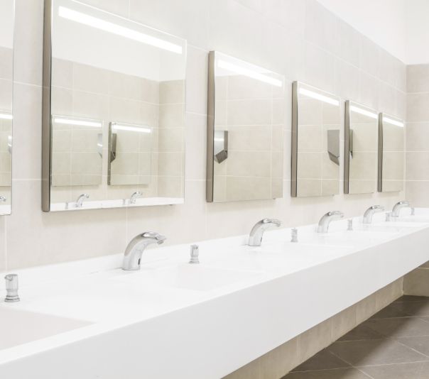 Modern public restroom sinks with mirrors and bright lighting.