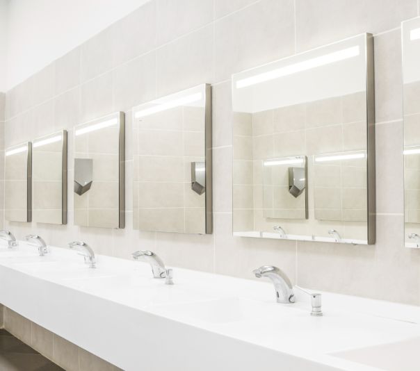 Modern restroom sinks with mirrors and soap dispensers.