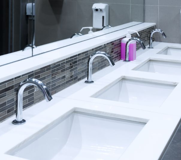 Modern restroom sinks with sleek faucets and soap dispensers.