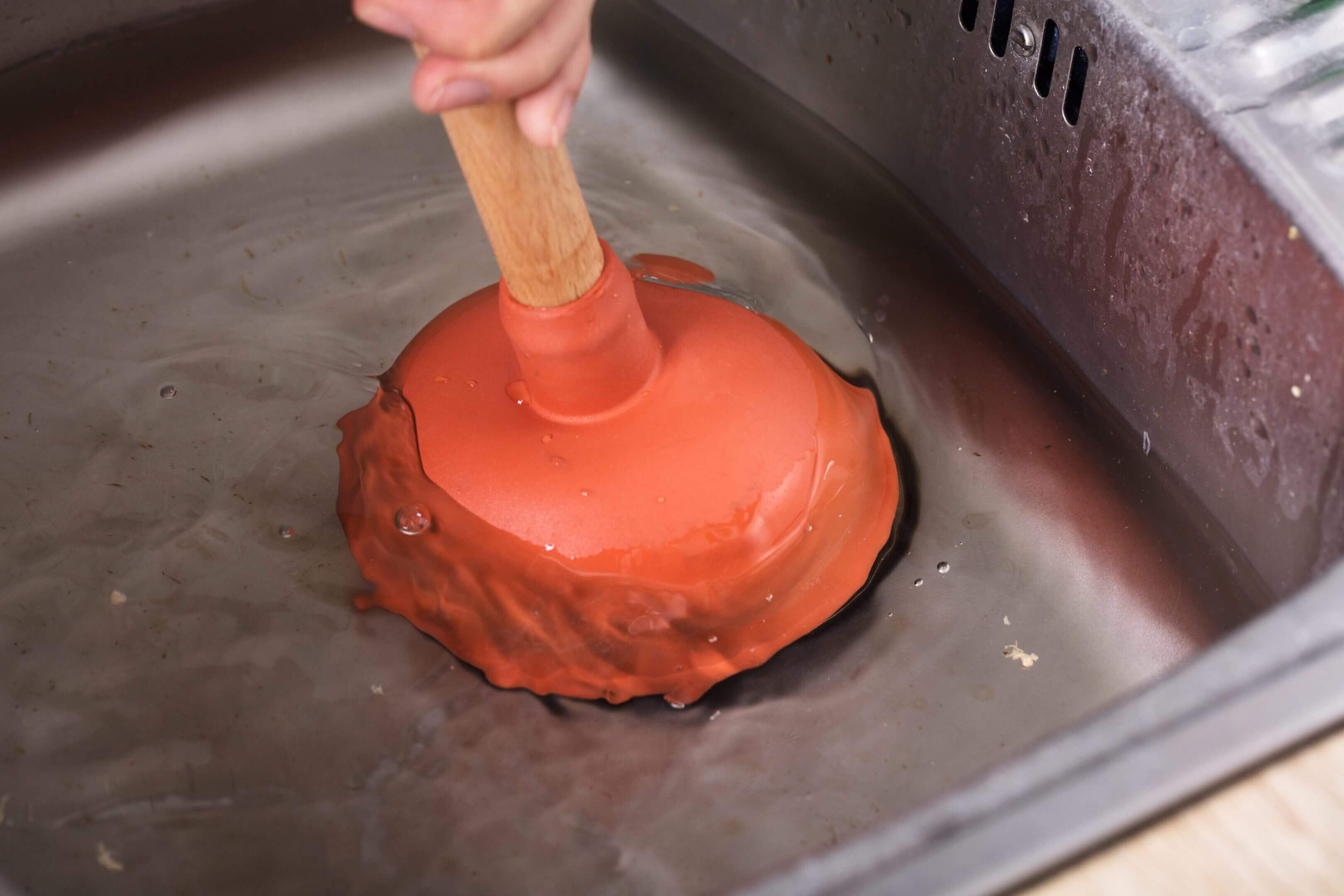 Plunger in action unclogging a kitchen sink.